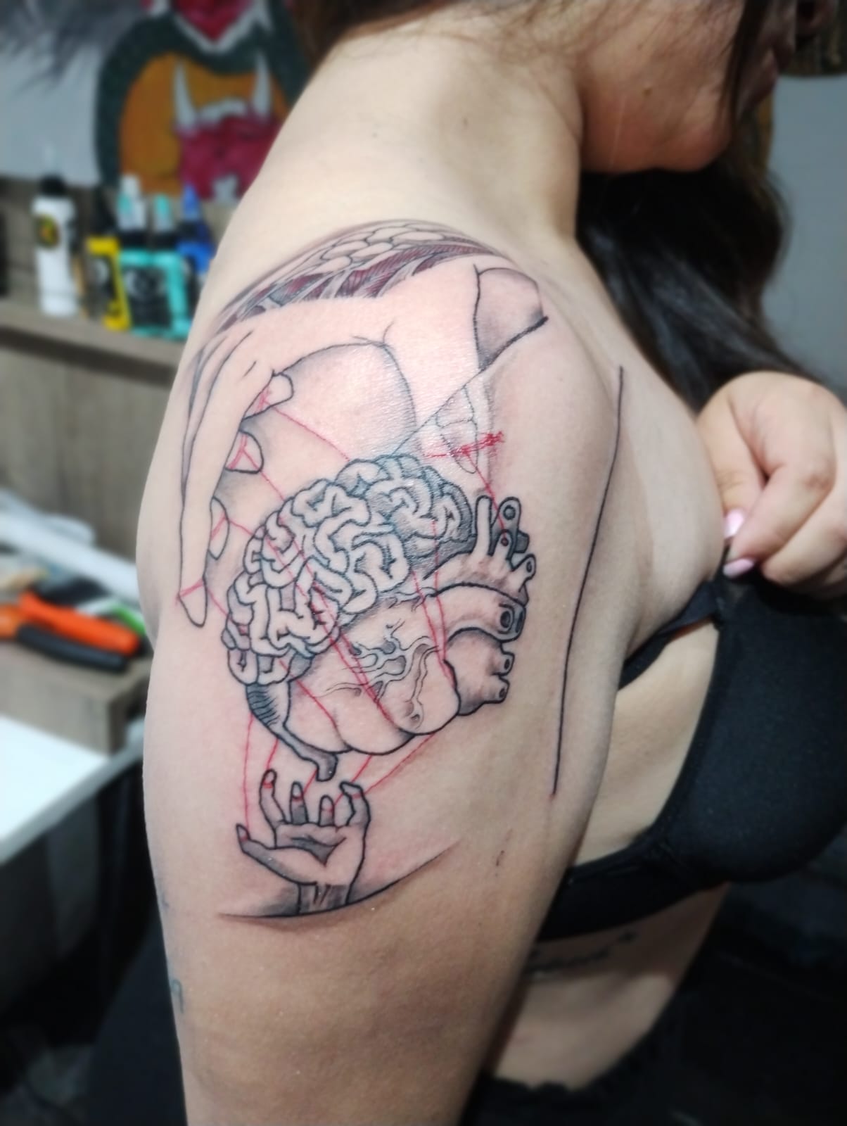 Tatuaje de corazón anatómico con flores en el brazo
